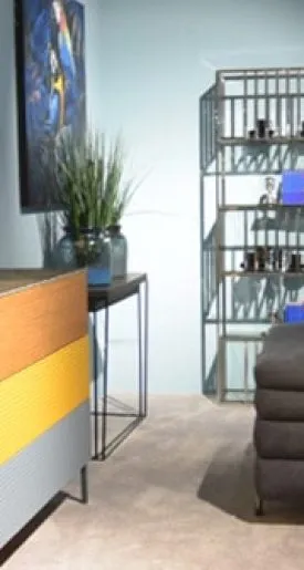 Wohnzimmer mit dunklem Sofa und bunter Holzkomode